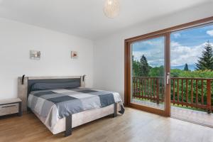 a bedroom with a bed and a balcony with a large window at Duplex la source Amelie in Saint-Pancrasse +34 photos