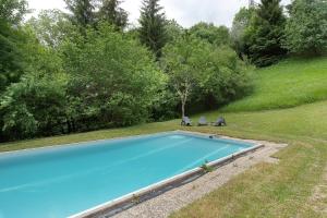 a swimming pool in a yard with two chairs at Duplex la source Amelie in Saint-Pancrasse