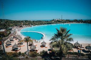 a large swimming pool with a beach and palm trees at Frontline Golf Penthouse Lagoon & SPA – EHHouse in Estepona