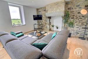 a living room with a couch and a stone wall at Ty jaudy in Trédarzec