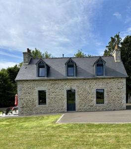 a brick house with a roof on a grass field at Ty jaudy in Trédarzec