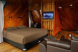 a bedroom with a bed and a couch and a television at Nimo Tea Resort in Tanara