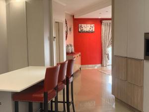 a kitchen with red walls and a counter with chairs at Mabee's Place in Durban
