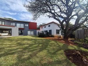 a house with a tree in front of a yard at Mabee's Place in Durban