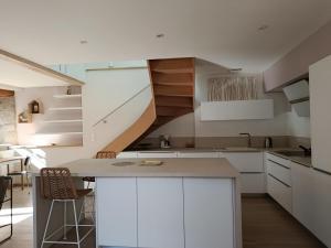 a kitchen with white cabinets and a spiral staircase at La maisonnette de colette in Chastel-Nouvel