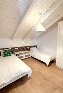 two beds in a room with white walls and wood floors at Posadas de Marí Casa Andreea 6 in Talavera de la Reina