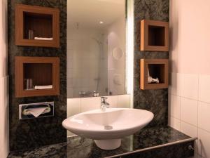 a bathroom with a white sink and a mirror at Mövenpick Hotel Münster am Aasee in Münster +123 photos