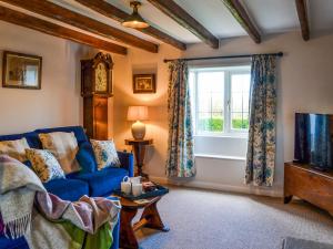 a living room with a blue couch and a window at Winship Cottage in Winestead +17 photos