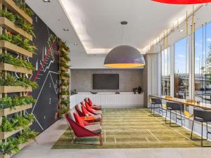 a lobby with red chairs and a wall with plants at ibis Styles Dubai Airport Hotel in Dubai