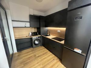 a small kitchen with black cabinets and a washer and dryer at Central View Penthouse & Parking in Târgu-Mureş