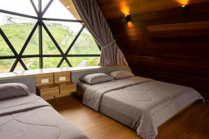 two beds in a room with a large window at Nimo Tea Resort in Tanara