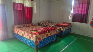 two beds in a room with green floors and windows at The Captain's Quarters in Ukhimath