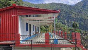 a red and white building with mountains in the background at The Captain's Quarters in Ukhimath