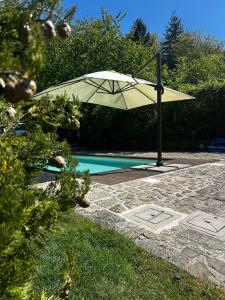 a white umbrella sitting next to a swimming pool at B&B Borgo Scola Paradise View in Vimignano