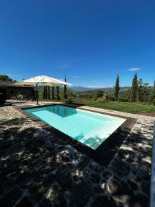 a swimming pool with an umbrella next to a house at B&B Borgo Scola Paradise View in Vimignano