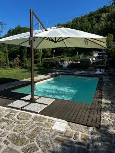 a large white umbrella next to a swimming pool at B&B Borgo Scola Paradise View in Vimignano