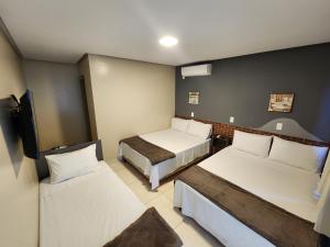 a hotel room with two beds and a tv at Pousada King in Vitória da Conquista