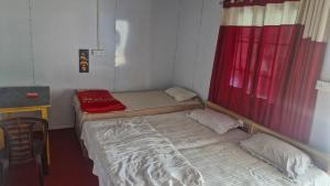 two beds in a room with a red window at The Captain's Quarters in Ukhimath