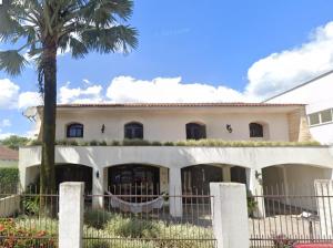 a white house with a palm tree and a fence at Casa Quarto 2 in Jaraguá do Sul