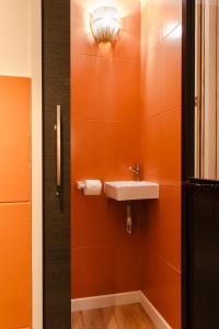 a bathroom with a sink and an orange wall at La Cave Voutée - Home Cinema in Valence +28 photos