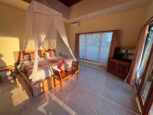 a bedroom with a canopy bed and a television at Intan Villa & Suite Ubud in Ubud