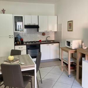 a kitchen with white cabinets and a table and a microwave at Casa Vacanza Margherita in Assemini +30 photos