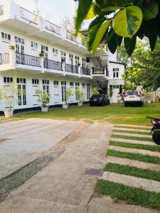 a large white building with cars parked in front of it at Lodge 52 in Negombo