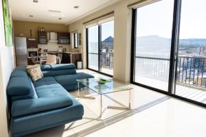 a living room with a blue couch and a glass table at Marsalforn Panorama Penthouse in Marsalforn