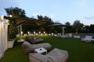 a lawn with couches and tables and umbrellas at Hotel The Brand in Rome