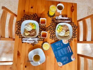 a wooden table with two plates of food and cups of coffee at La Curadiña - Encuentro Surf Hotel in Cabarete