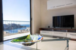 a living room with a glass table and a television at Marsalforn Panorama Penthouse in Marsalforn