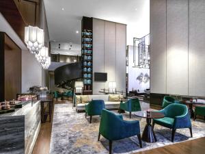 a hotel lobby with green chairs and tables at Pullman Bandung Grand Central in Bandung