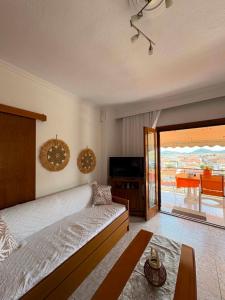 a bedroom with a bed and a television and a balcony at Thalia Sea View Apartment in Nea Peramos