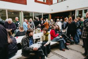 a crowd of people sitting on benches outside a building at Snuffel Youth Hostel in Bruges