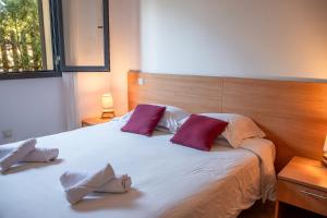 a bedroom with a large white bed with two purple pillows at Résidence Guddelmoni, Piscines chauffées in Propriano