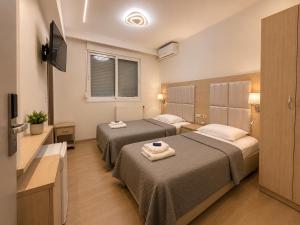 a hotel room with two beds and a flat screen tv at Hotel Avra in Perea +20 photos