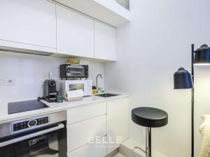 a kitchen with white cabinets and a microwave and a stool at Rocher - 3min Port Hercule - Casino in Monte Carlo