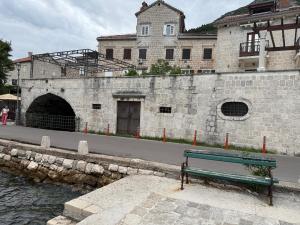 a bench sitting in front of a building next to the water at Apartment Forteca Lux in Perast +25 photos