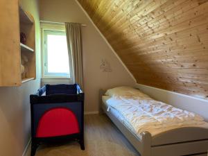 a bed in a room with a wooden ceiling at Vakantiehuis 44 op Recreatiepark De Wielen in Sint Maarten +23 photos
