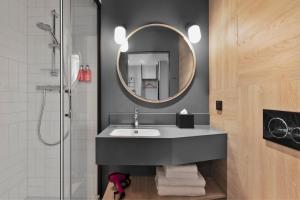 a bathroom with a sink and a mirror at Moxy Szczecin City in Szczecin +31 photos