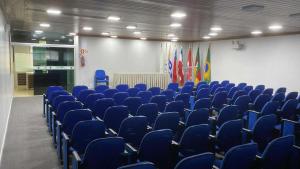 an empty room with blue chairs and flags at Fares Turis Hotel in Uruguaiana