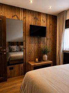 a bedroom with a bed and a tv on a wooden wall at Appartamento Arisch in Aprica