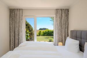 a bedroom with a bed and a large window at Boddenweite 3 in Born