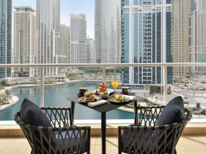a table with a plate of food on a balcony at Mövenpick Hotel Jumeirah Lakes Towers Dubai in Dubai