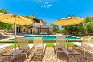 a group of chairs and umbrellas next to a swimming pool at Villa Bandris by Slow Villas in Manacor