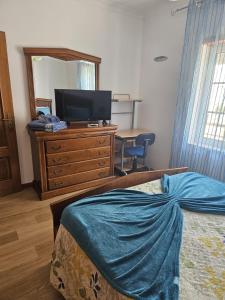 a bedroom with a bed and a dresser with a television at BigWaves2 in Nazaré