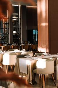 a dining room with tables and white chairs at Ilyonis Hotel & Spa in Shëngjin