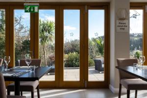 a dining room with sliding glass doors and a table and chairs at The Llawnroc Hotel in Gorran Haven