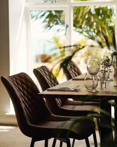 a wooden table with chairs and wine glasses on it at The Llawnroc Hotel in Gorran Haven