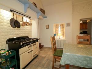 a kitchen with a stove and a table with a table gmaxwell gmaxwell gmaxwell at Rosslare Cottage in Broughshane